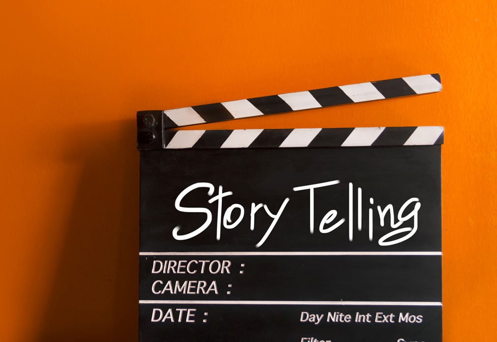 "Storytelling" handwritten on a clapperboard in front of an orange background?