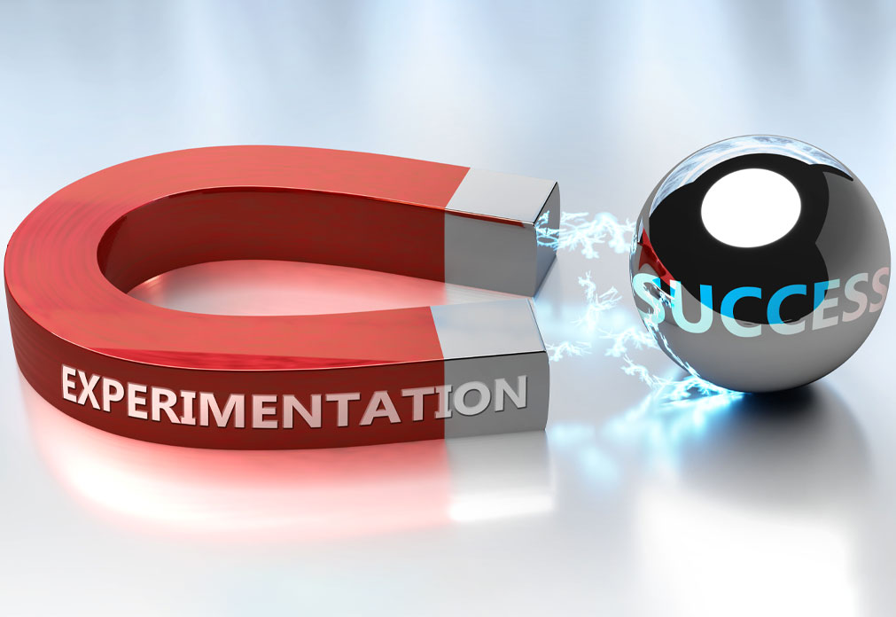 Magnet with the text "Experimentation" on it pointed at a metal ball with "Success" written on it