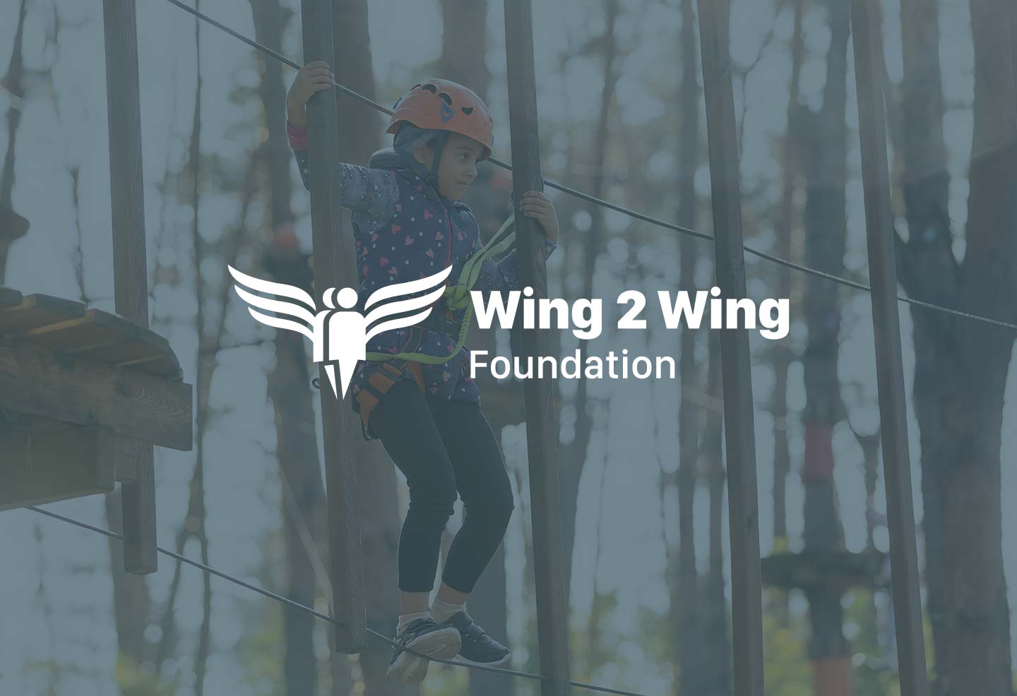 Child using zip lining course with white text that says "Wing 2 Wing Foundation" over the child