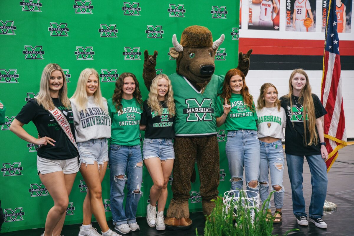 High school students stand proudly next to their new university mascot, Marco the Bison