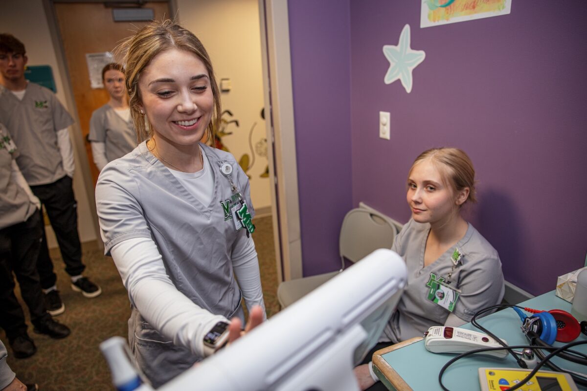 A medical student smiles during a hands-on learning exercise as part of the Marshall University Med-Ex Tour.