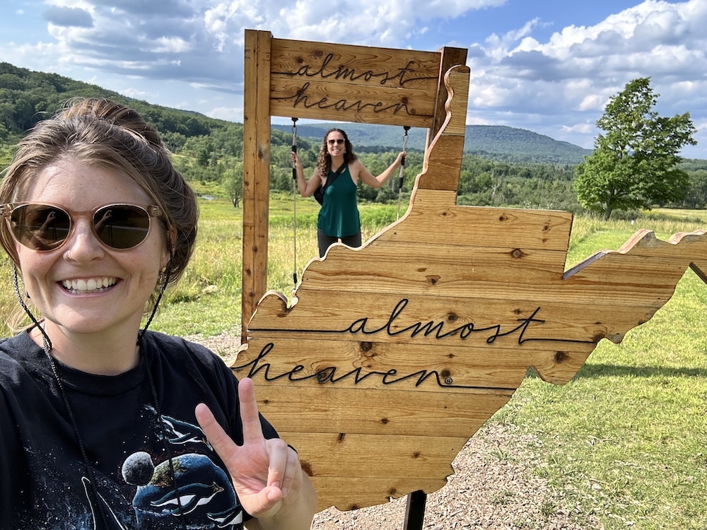 First Ascenders stand smiling in front of the “Country Roads” photo swing.