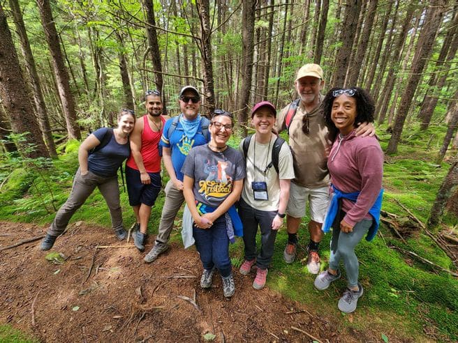 First-Ascent-Remote-Work-in-the-Wild First Ascent members gather together on a hiking trail, smiling together.