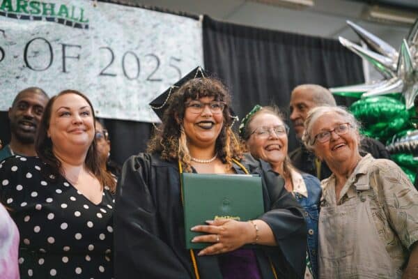 A Marshall University graduate stands next to her family after she crosses the stage at commencement.