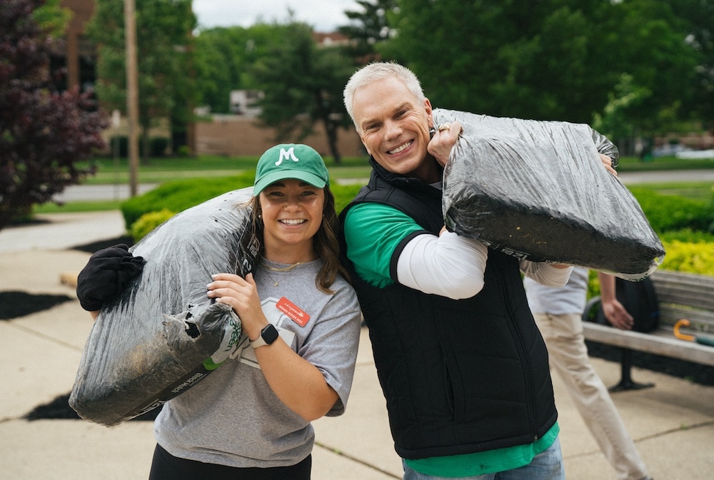 President Smith smiles with a Marshall student holding soil during Community Cares Week 2025